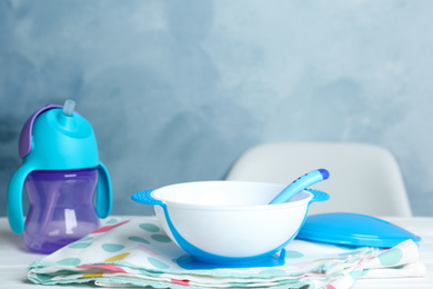 Photo of Set of plastic dishware on white table. Serving baby food