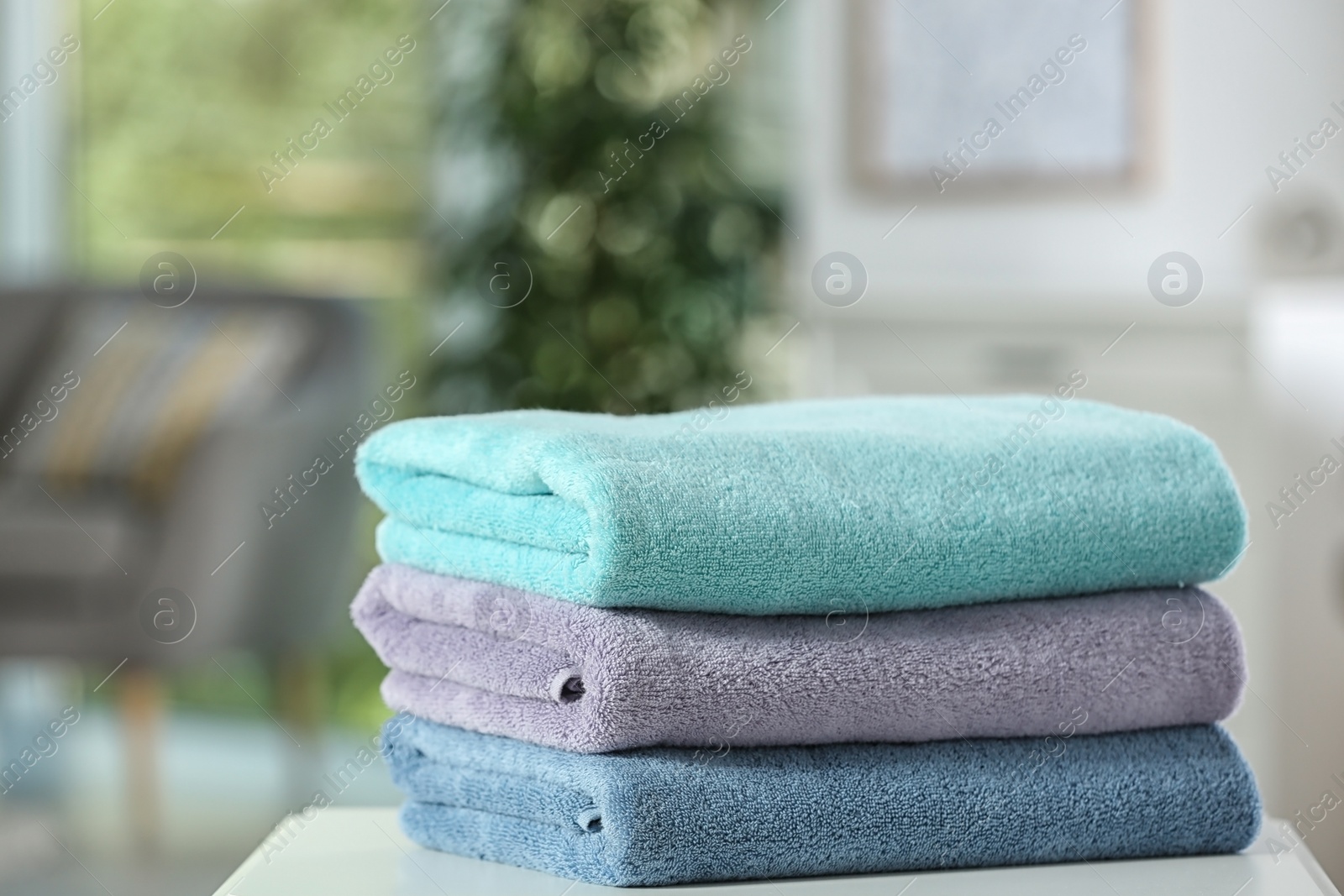 Photo of Stack of folded clean soft towels on table indoors