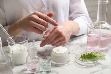 Photo of Scientist testing cosmetic product at white marble table in laboratory, closeup