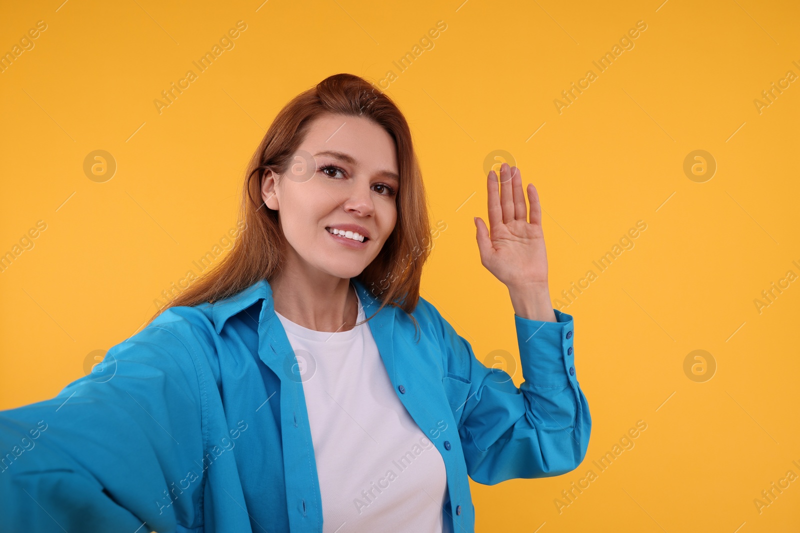 Photo of Beautiful woman taking selfie on orange background