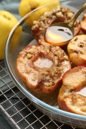 Photo of Pouring tasty honey onto baked quinces in bowl on table, closeup