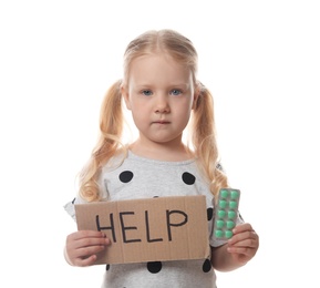 Photo of Little child with pills and word Help written on cardboard against white background. Danger of medicament intoxication