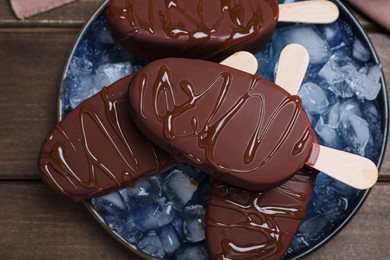 Photo of Delicious glazed ice cream bars and ice cubes on wooden table, top view