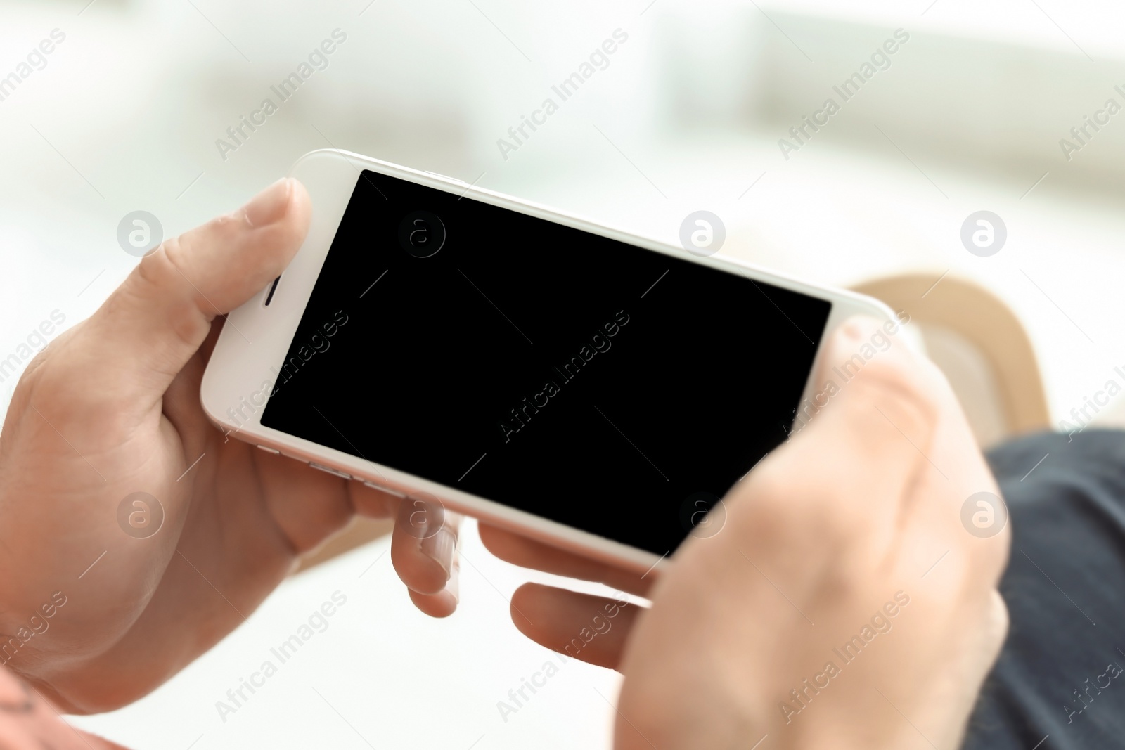 Photo of Man holding mobile phone with blank screen on blurred background, closeup. Mockup for design