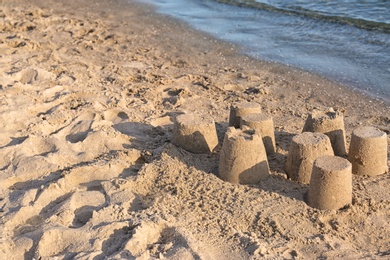 Photo of View of beach with little sand figures near sea on sunny summer day. Space for text