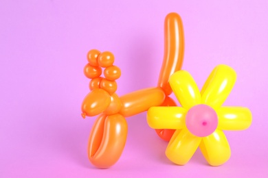 Photo of Flower and animal figures made of modelling balloons on color background. Space for text