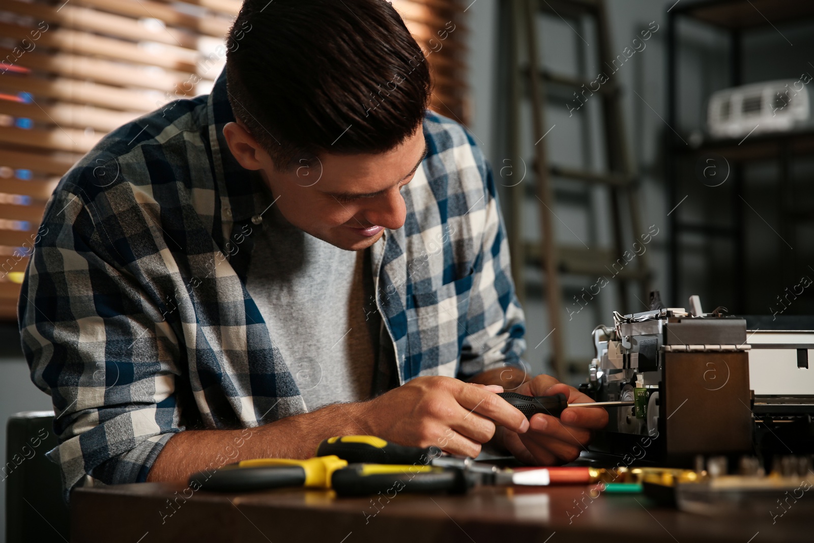 Photo of Repairman with screwdriver fixing modern printer in office