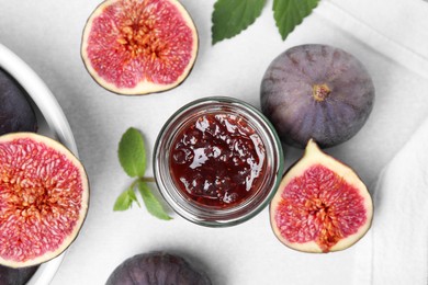 Photo of Glass jar of tasty sweet fig jam and fruits on light table, flat lay