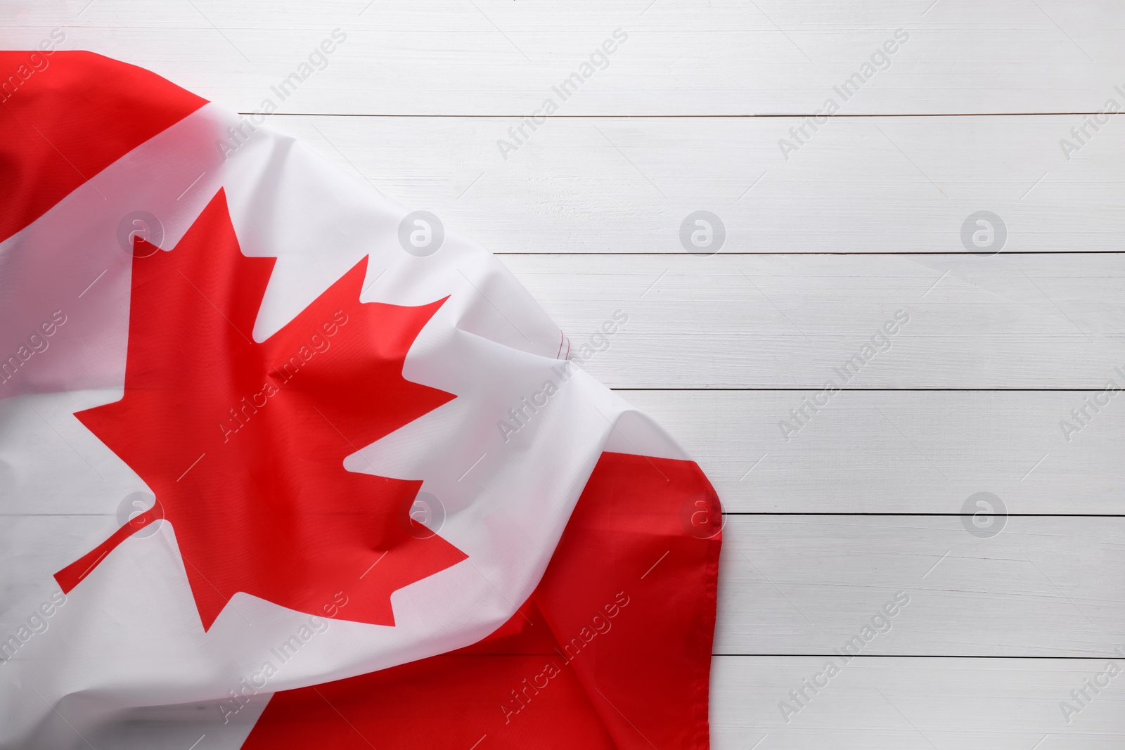 Photo of Flag of Canada on white wooden table, top view. Space for text