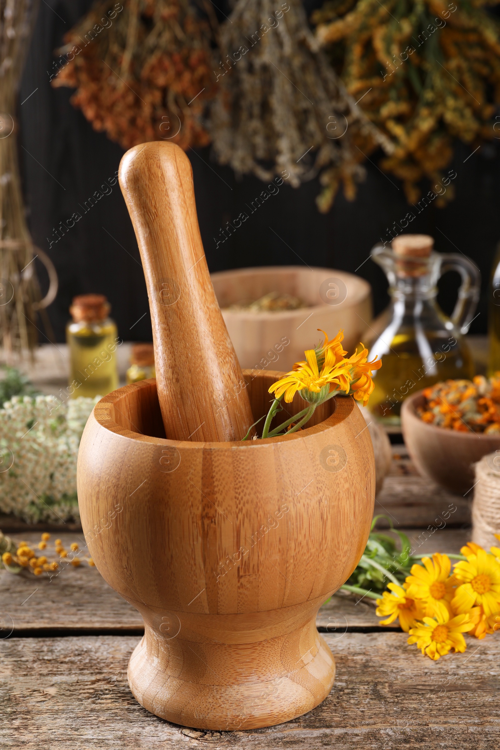 Photo of Mortar with pestle and calendula flowers on wooden table. Medicinal herbs