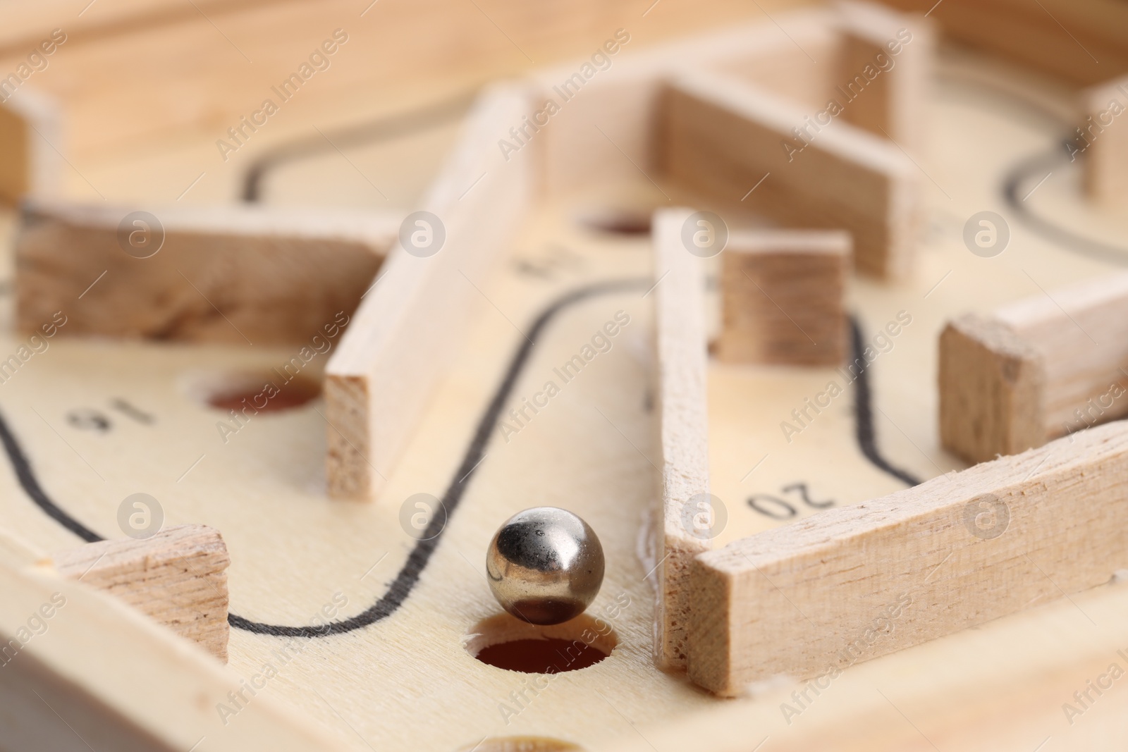 Photo of Wooden toy maze with metal ball, closeup