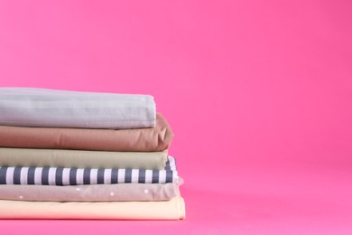Photo of Stack of clean bed sheets on pink background. Space for text