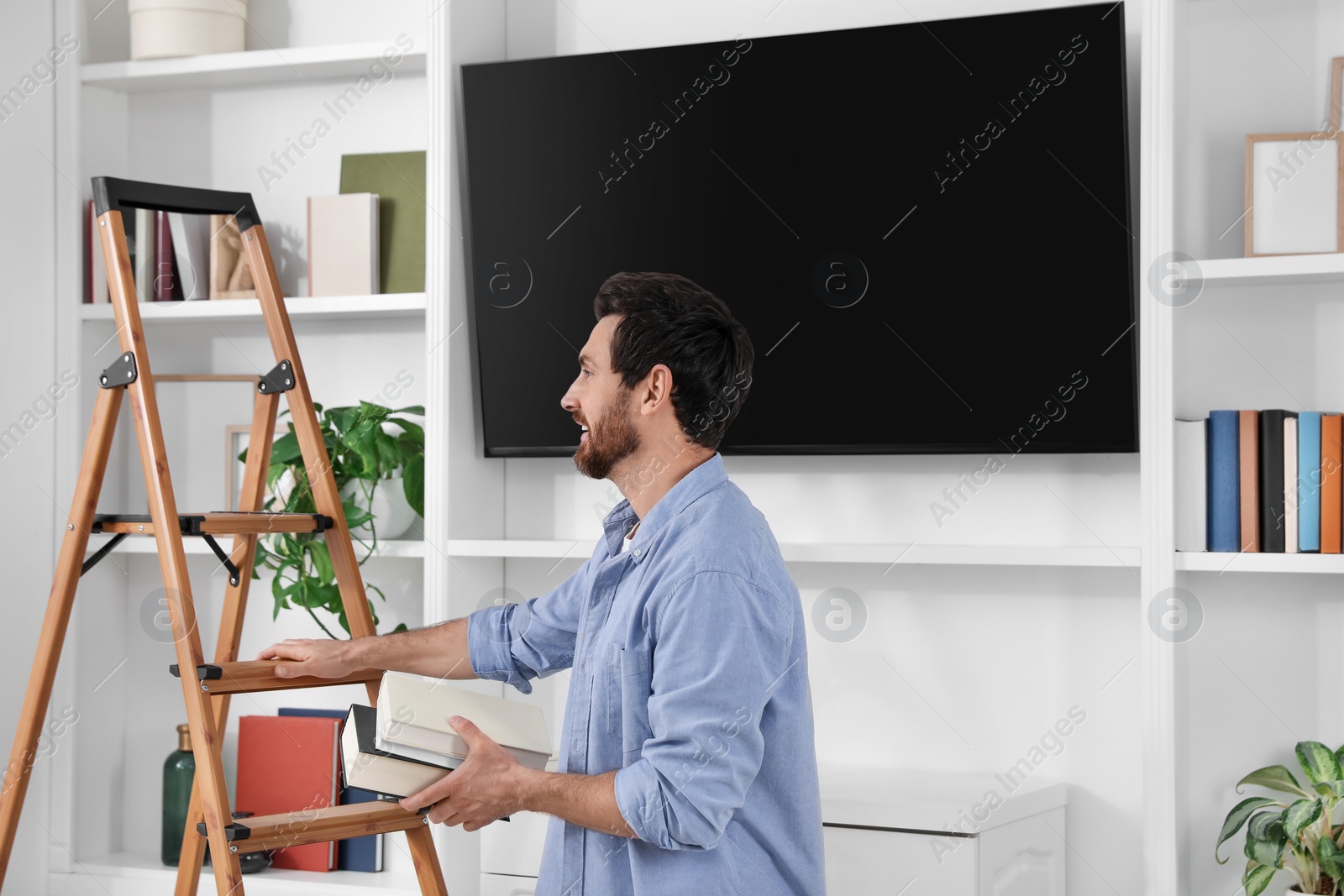 Photo of Man with books near wooden folding ladder at home