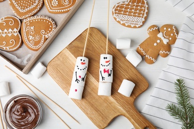 Photo of Flat lay composition with funny snowmen made of marshmallows on white wooden table