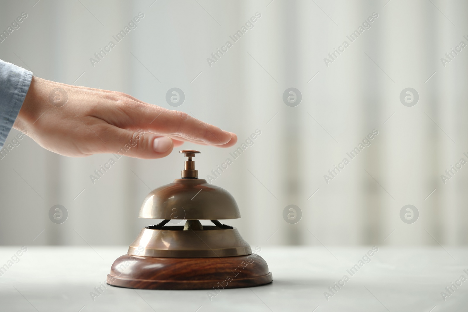 Photo of Man ringing hotel service bell at table indoors, closeup. Space for text