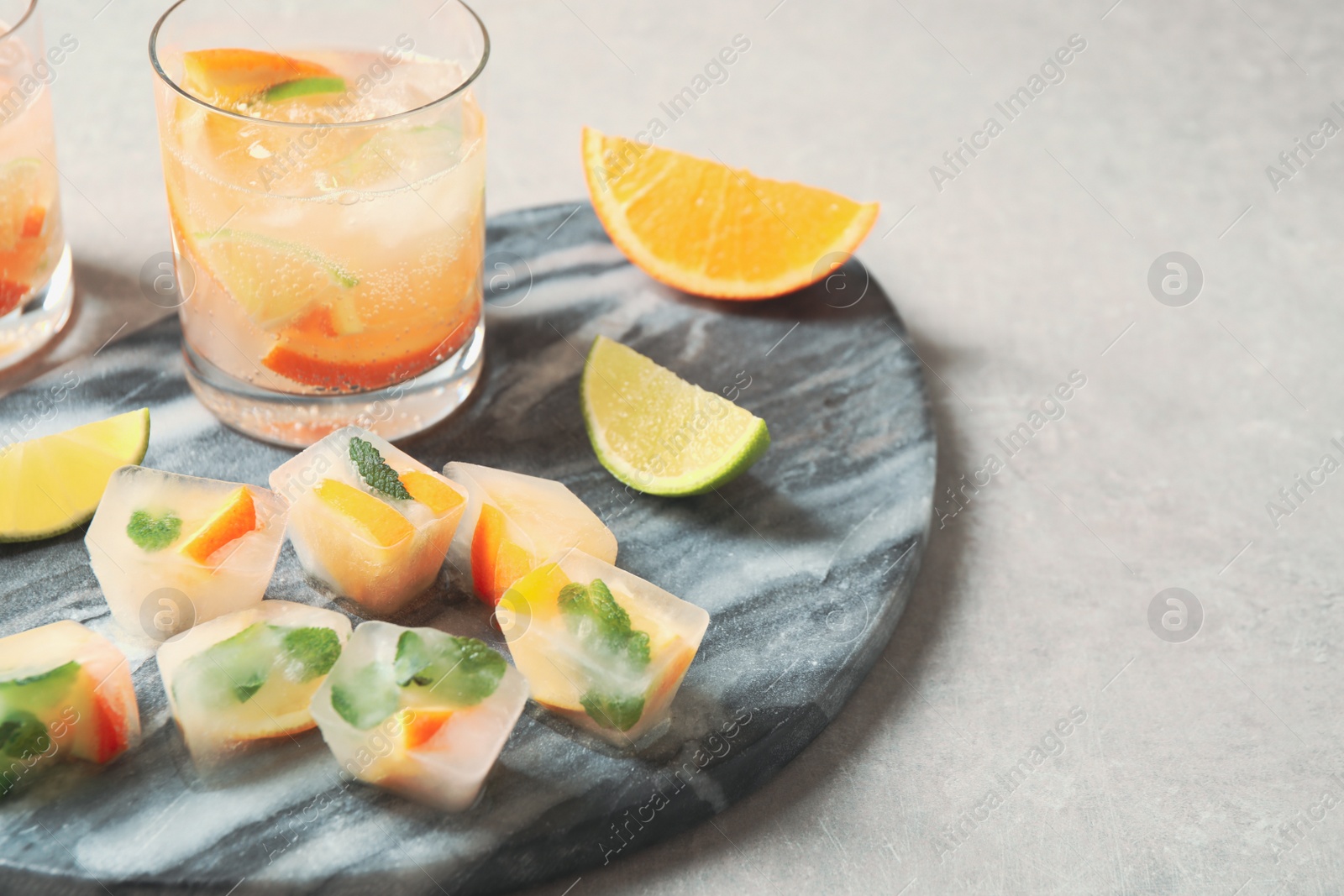 Photo of Ice cubes with orange and mint on light grey table