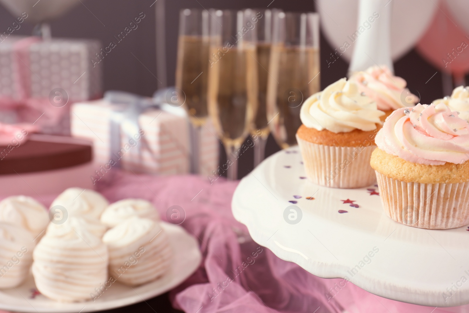 Photo of Stand with cupcakes on table, closeup. Space for text