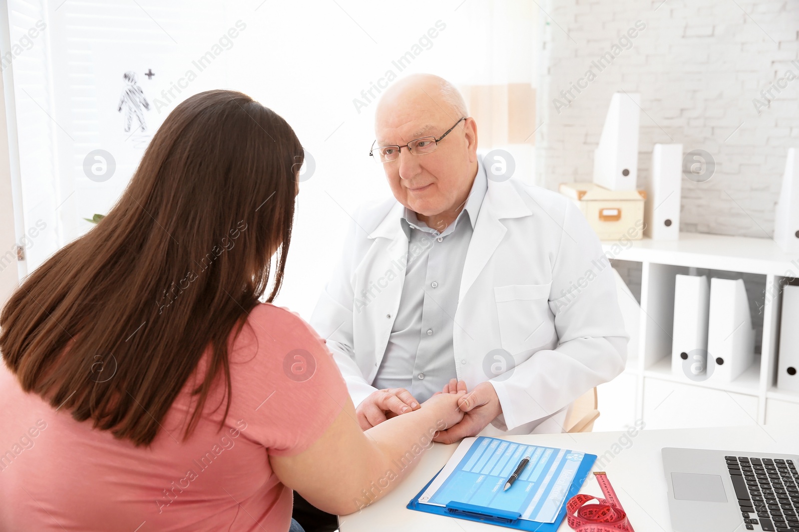 Photo of Doctor taking pulse of overweight woman in clinic