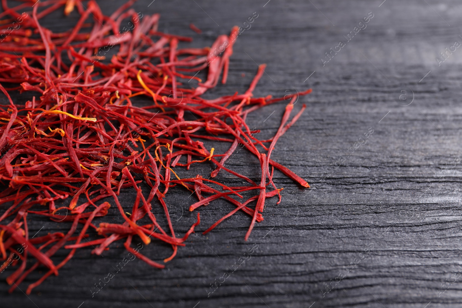 Photo of Dried saffron on black wooden table, space for text