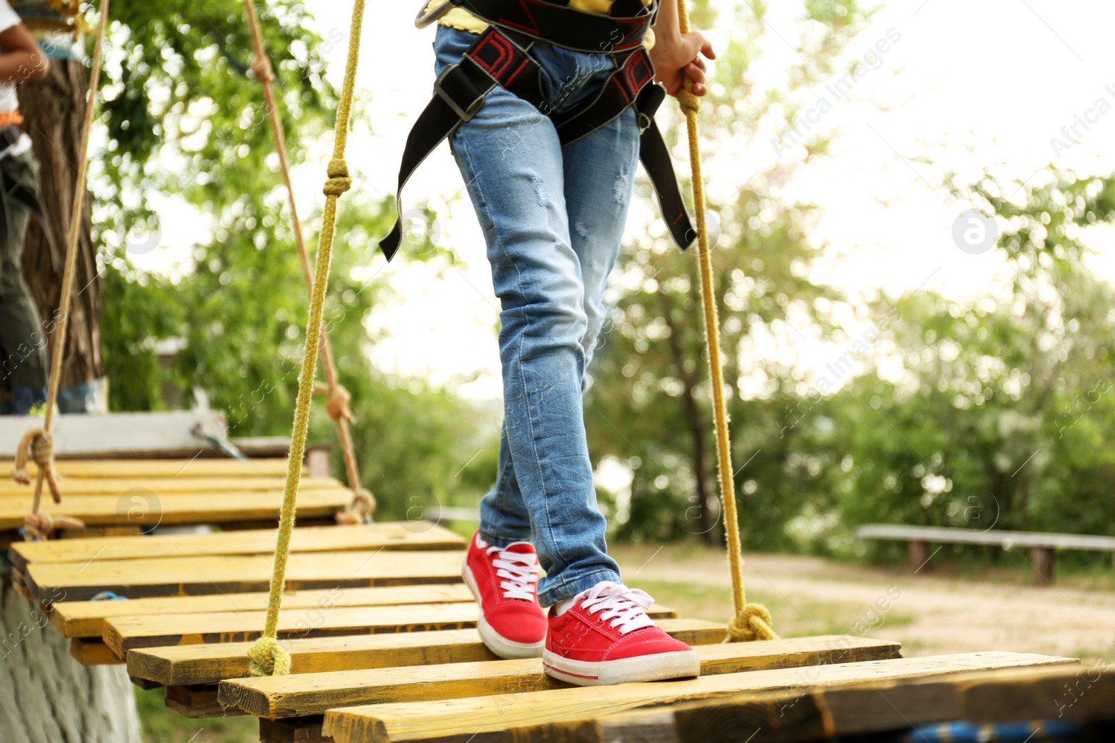 Photo of Little girl climbing in adventure park, closeup. Summer camp