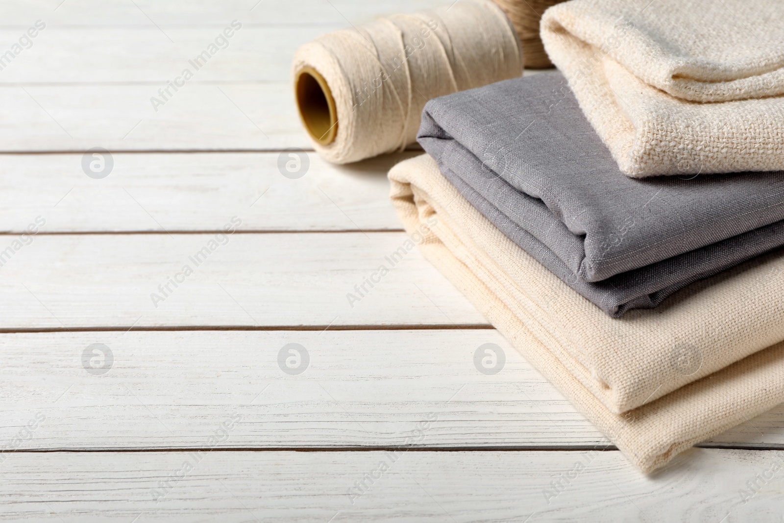 Photo of Hemp cloths and thread on white wooden table, space for text