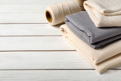 Hemp cloths and thread on white wooden table, space for text