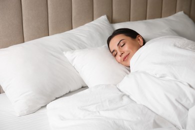 Photo of Young woman sleeping in bed covered with white blanket