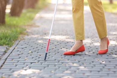 Photo of Blind woman with cane walking on city street, closeup