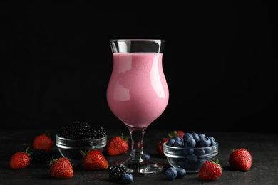 Tasty milk shake and fresh berries on black slate table