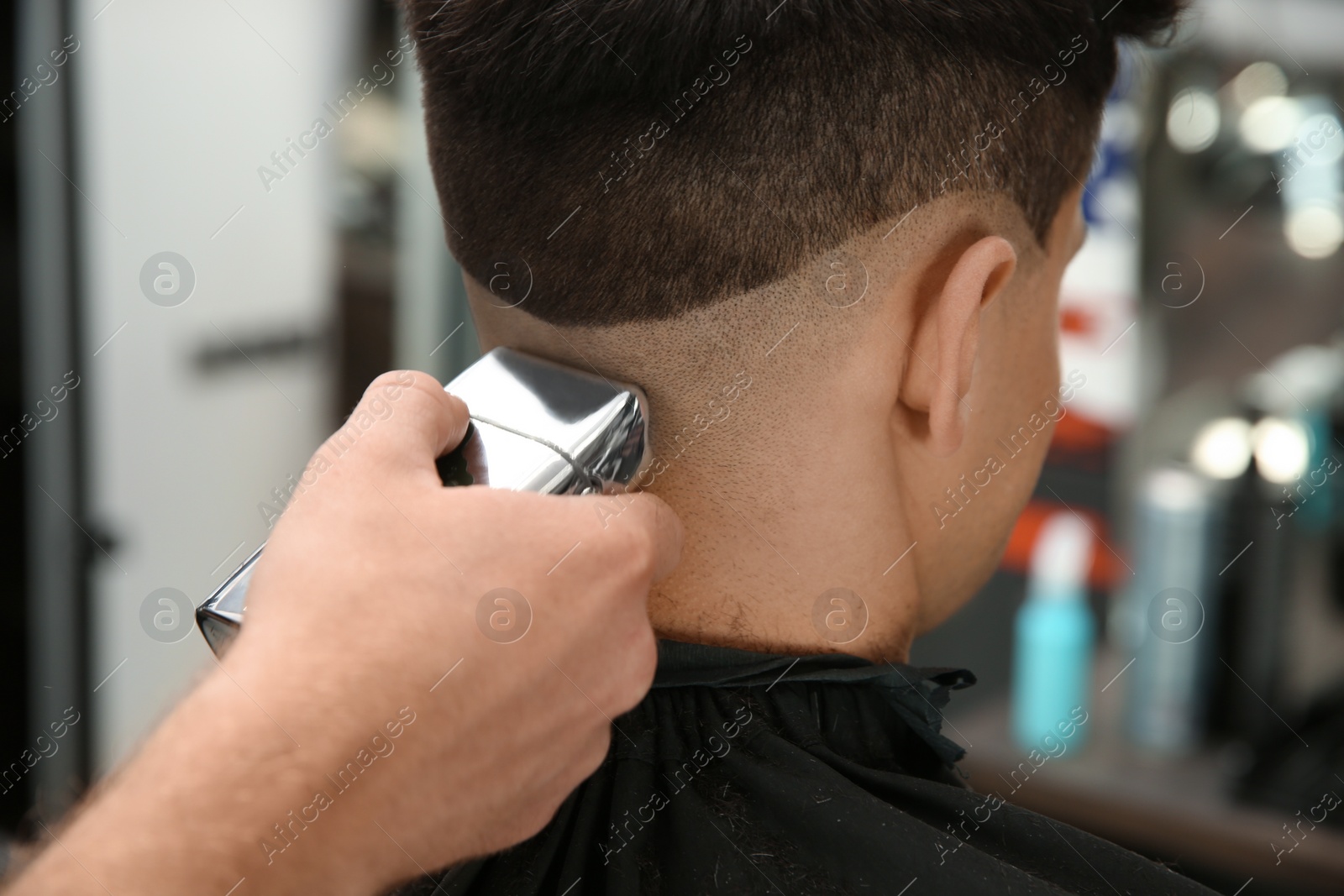 Photo of Professional barber making stylish haircut in salon, closeup