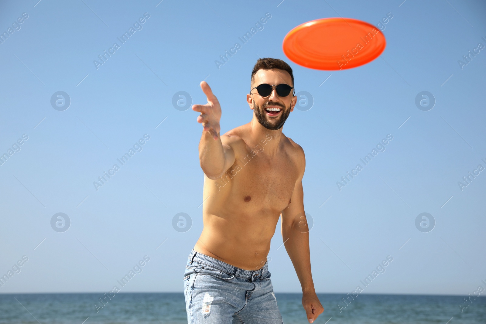 Photo of Happy man throwing flying disk at beach on sunny day