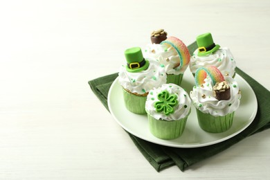 St. Patrick's day party. Tasty festively decorated cupcakes on white table. Space for text