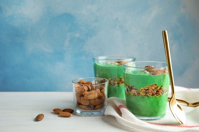 Photo of Composition with glass cups of spirulina smoothie on table against color background. Space for text