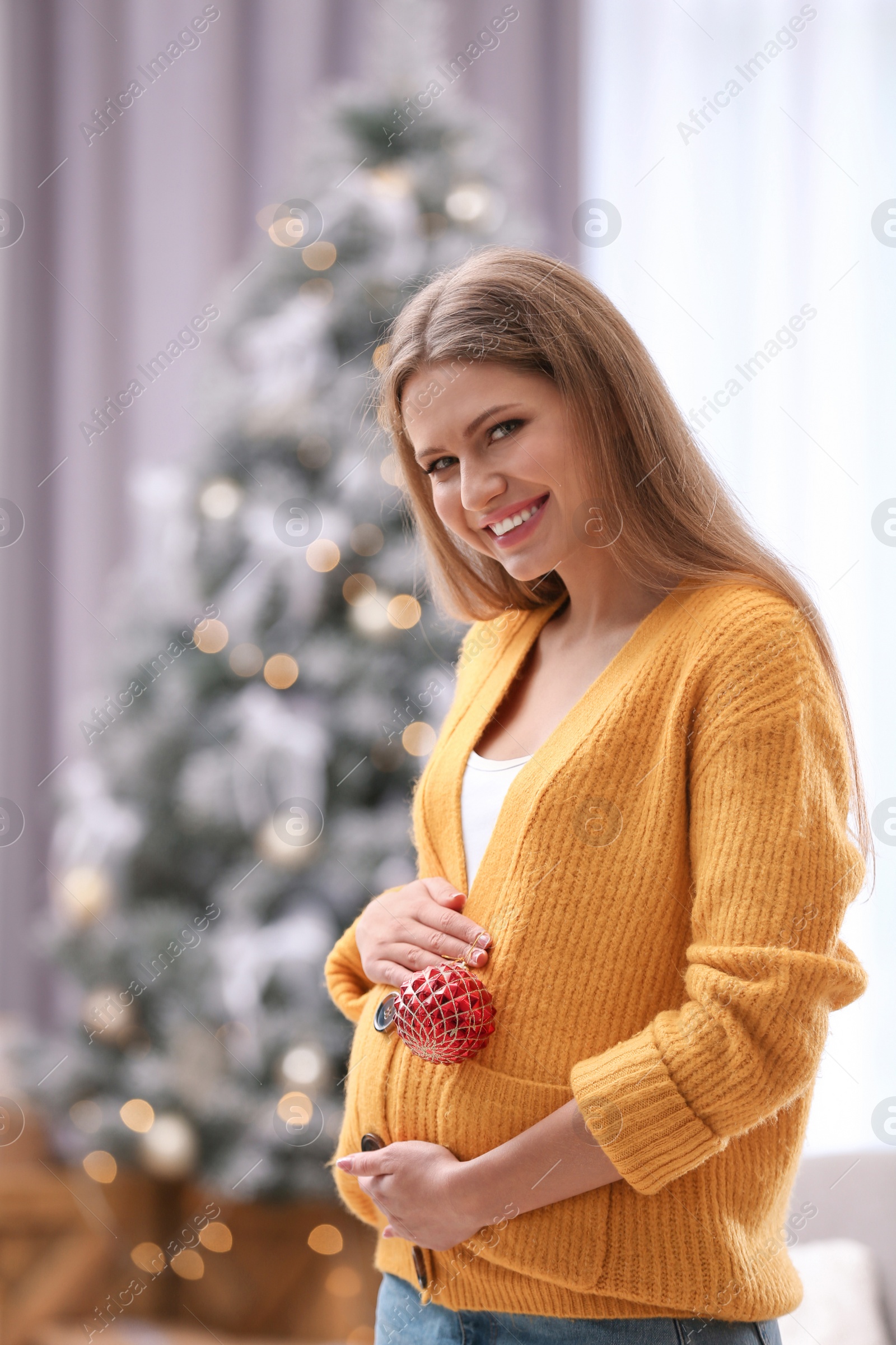 Photo of Young pregnant woman with Christmas decoration at home