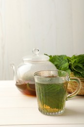 Photo of Aromatic nettle tea on white wooden table, space for text