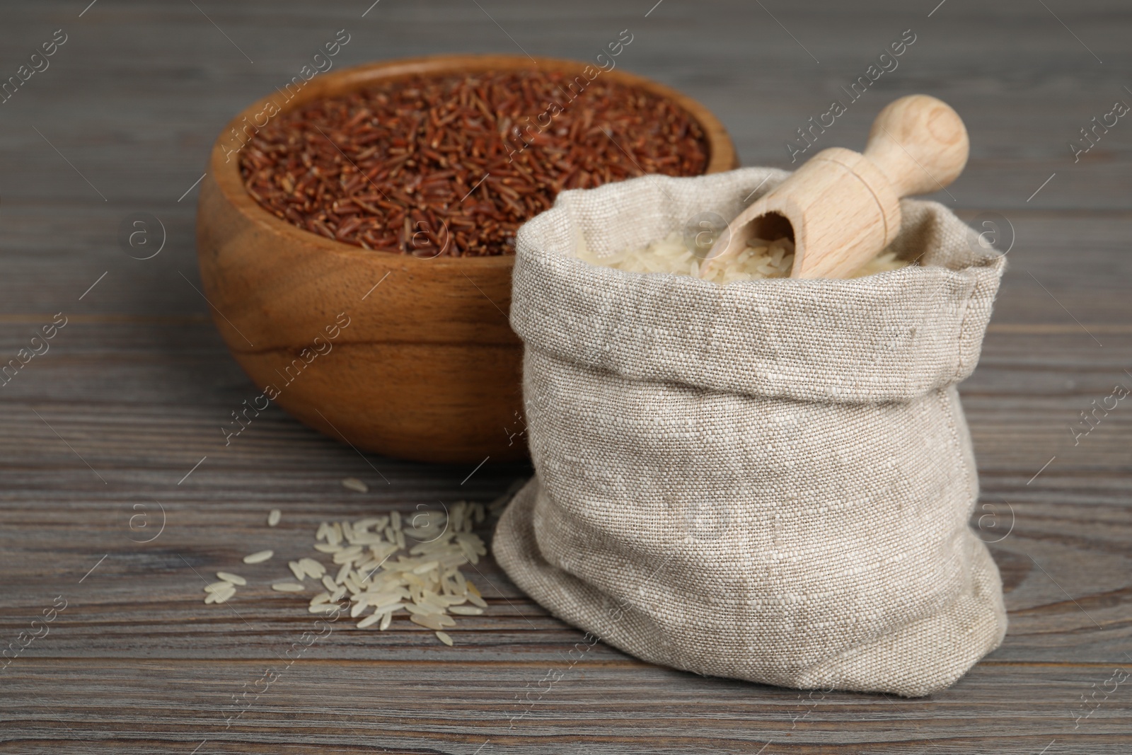 Photo of Bag and bowl with different sorts of rice on wooden table