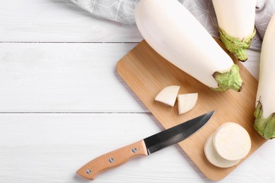 Photo of Board, raw white eggplants and knife on wooden table, flat lay. Space for text