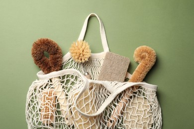 Photo of Bag with eco friendly products on green background, flat lay. Conscious consumption