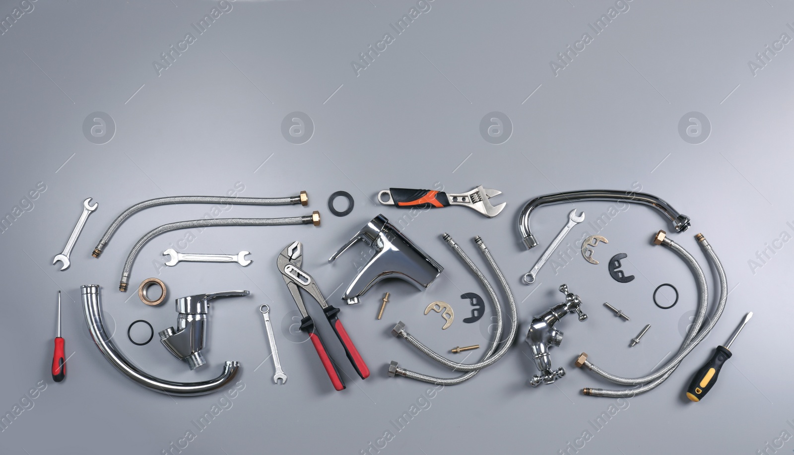 Photo of Parts of water tap and plumber tools on grey background, flat lay