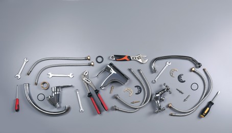 Photo of Parts of water tap and plumber tools on grey background, flat lay