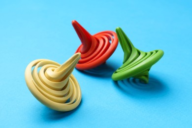 Photo of Many colorful spinning tops on light blue background, closeup