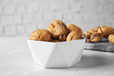 Photo of Bowl of tasty dried figs on light grey marble table, closeup
