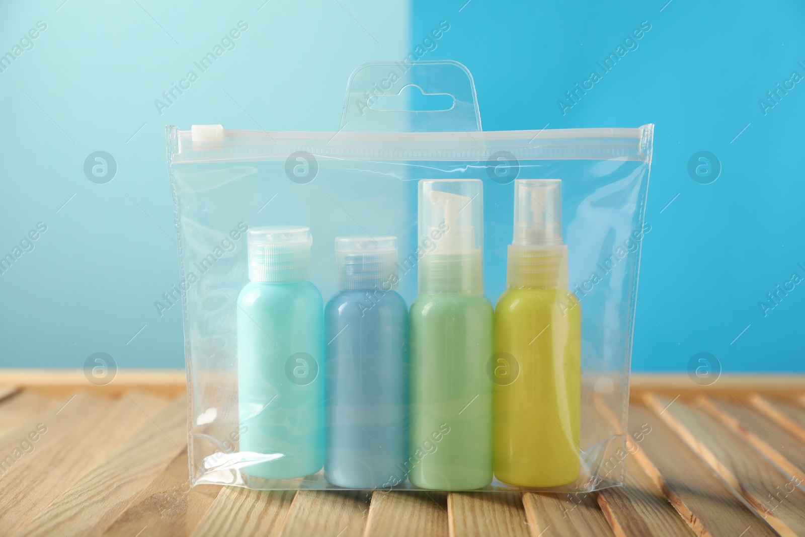 Photo of Cosmetic travel kit in plastic bag on wooden table. Bath accessories