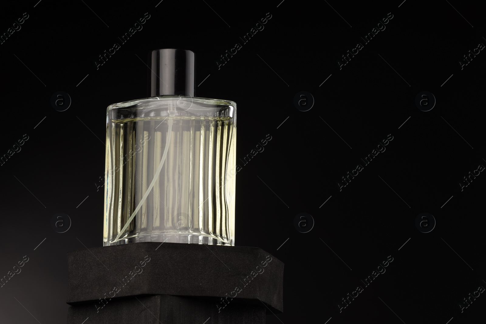 Photo of Luxury men`s perfume in bottle against dark background, space for text