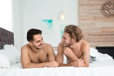 Happy gay couple lying on bed at home