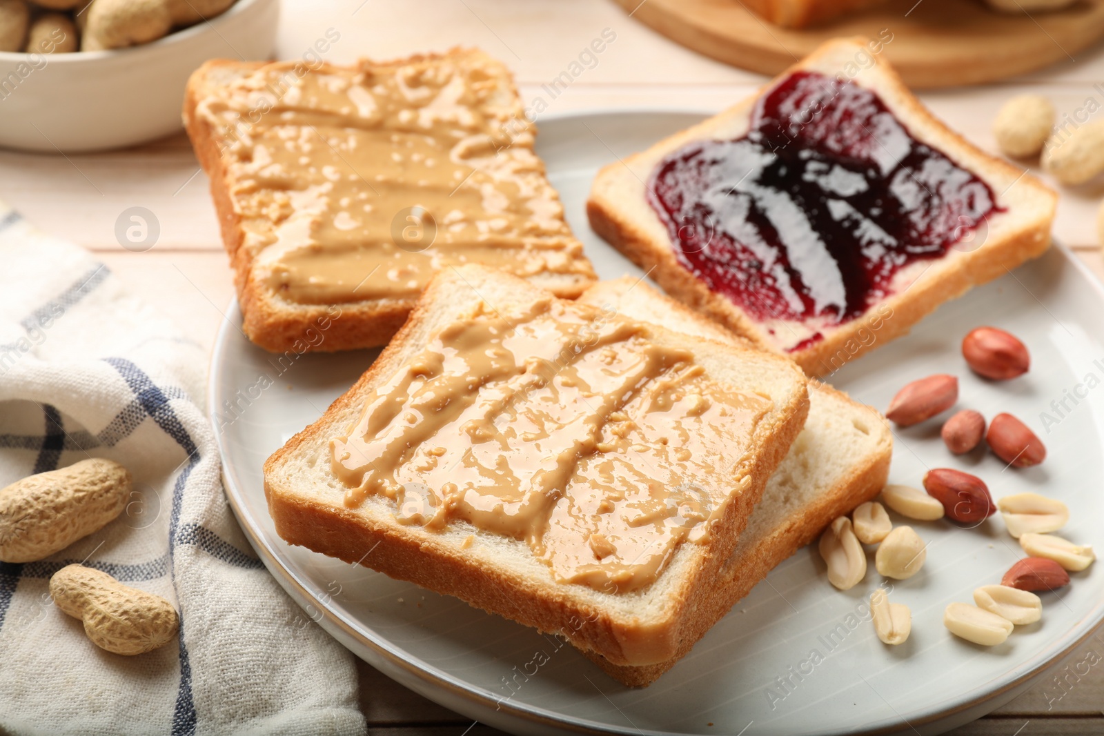 Photo of Delicious toasts with peanut butter, jam and nuts on table, closeup