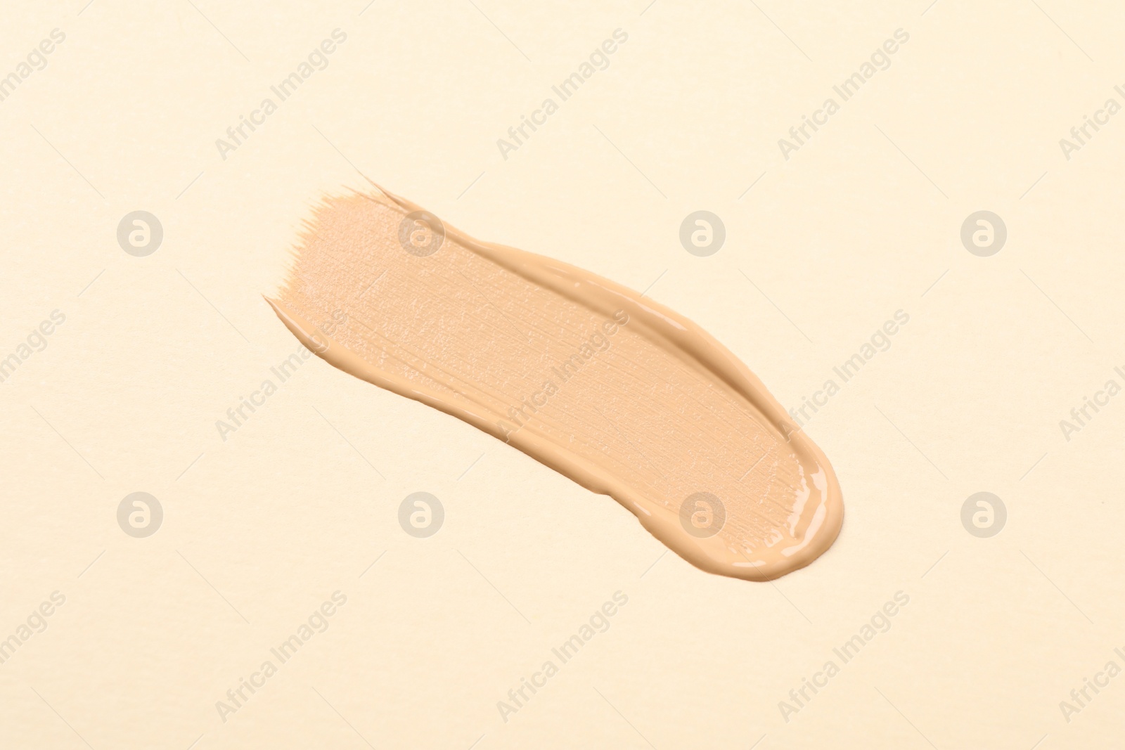 Photo of Smear of skin foundation on beige background, top view