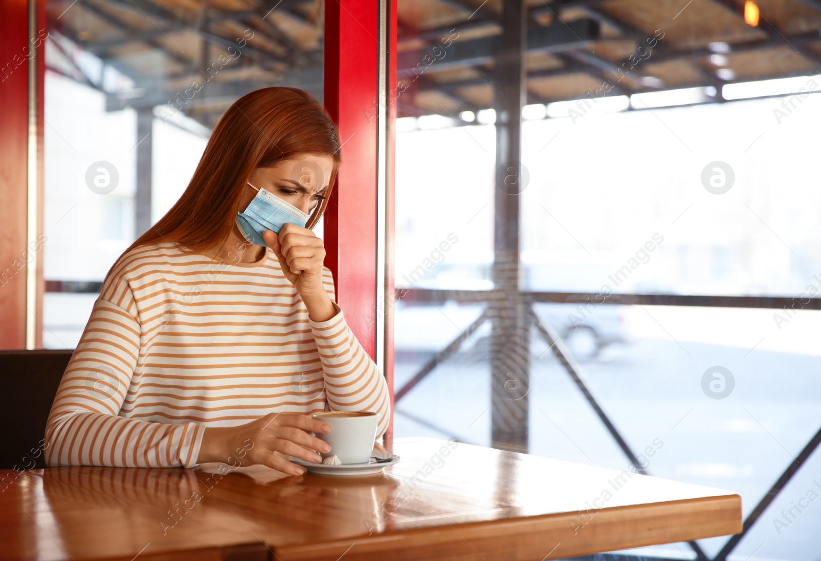 Photo of Woman with medical mask in cafe. Virus protection