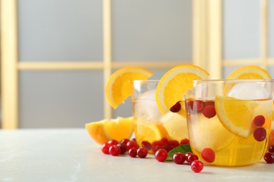 Photo of Delicious cocktails with orange, cranberries and ice balls on light grey marble table. Space for text