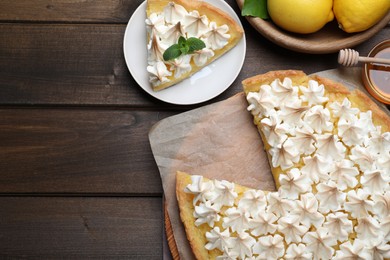 Photo of Cut delicious lemon meringue pie served on wooden table, flat lay. Space for text